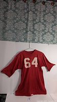 Front view of red football jersey with number 64 on front and back