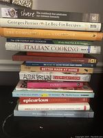 Stack of assorted cookbooks on various cuisines with visible titles.