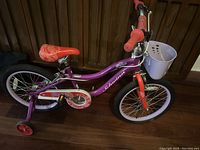 Side view of purple Schwinn kids bike with pink training wheels and white front basket