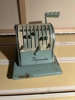 Front view of vintage Paymaster check writer machine showing multiple levers and brand name.