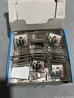Box filled with stacked vintage Three Stooges square magnets showing the front faces with images.