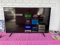 Front view of TCL Roku TV displaying Roku home screen with apps and inputs