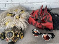 Photo showing three Halloween masks: red devil, yellow demon with white hair, and gas mask style mouth cover with goggles.