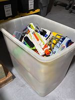 Large bin filled with assorted toys including toy guns and vehicles