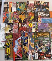 Top-down view of 25 assorted comic books showing colorful comic covers with various superhero and fantasy artwork.