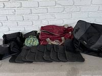Full view of all carry bags and felt liners laid out on ground against white brick wall