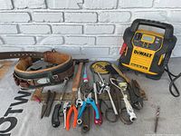 Full view of assorted tools including hand tools, tool belt, and DeWalt jump starter.