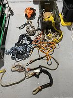 First photo of ropes, harnesses, carabiners and other climbing gear laid out on floor