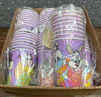 Box containing 13 sleeves of Easter-themed Looney Tunes Babies disposable cups wrapped in plastic, showing various characters and colorful Easter eggs on a purple background.