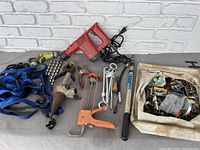 Wide photo showing the full lot: Hilti power tool, straps, bits, hand tools, hammer, rope, and bag full of nuts and bolts.