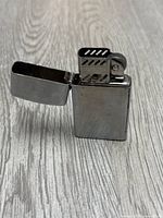 Opened lighter showing the ignition and wick area and loose top cover