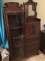 Full front view of oak secretary/bookcase showing glass-fronted bookcase left and mirrored drop-front desk right
