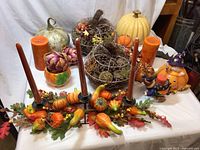 Autumnal décor with pumpkins, candles, and fall floral centerpiece on a table.