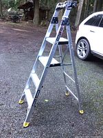 Full view of the Gorilla folding aluminum ladder standing outdoors, showing steps, side rails, and yellow rubber feet