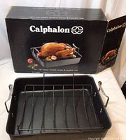 Photo of the roaster pan and roasting rack outside the box showing the black nonstick finish and metal handles.
