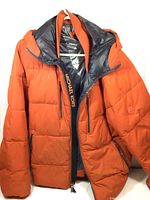 Front view of orange Michael Kors padded jacket with hood, showing zipper and pockets.