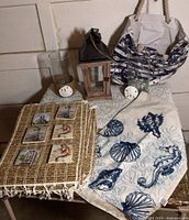 Overall lot showing woven place mats, table runner, lantern, glass vases, tote bag with anchor, and decorative coasters