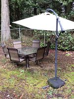 Overall view of hexagonal glass-top table with six chairs and offset umbrella