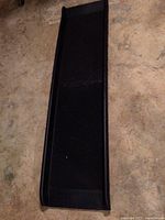 Photo showing the full length of the black plastic pet ramp folded on a concrete floor.