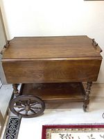 Wood tea cart closed with leaves down, showing large wooden wheels and lower shelf.