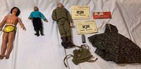 Photo showing three male dolls in various outfits and military accessories including manuals and poncho