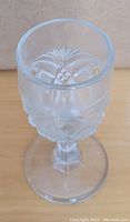 Clear glass sherry or cordial glass with pressed leaf and geometric patterns, showing the detailed design and faceted stem.