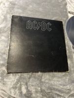 Front cover of the AC/DC vinyl record album showing the band's logo in silver on black background with visible wear.