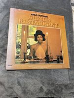 Front cover of the Arlo Guthrie Alice's Restaurant vinyl record album showing Arlo Guthrie at a table with candles.