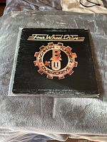 Front cover of Bachman-Turner Overdrive Four Wheel Drive vinyl showing band logo gear design with worn edges and surface wear.