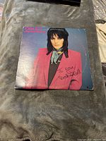 Front cover of the Joan Jett & The Blackhearts vinyl album with the artist wearing a bright pink jacket and the album signed with "I love Rock 'n Roll"