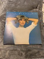 Front cover of Olivia Newton-John Dont Stop Believin album showing blue background and artist portrait.