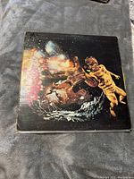 Front cover of Santana vinyl record album featuring cosmic and surreal artwork with colorful bursts and abstract human figures, showing wear and handwritten initials.