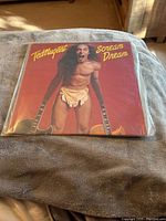 Front cover of Ted Nugent Scream Dream vinyl album showing Ted Nugent shirtless with two guitars.