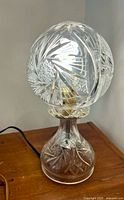 Lamp lit showing cut glass globe shade and base