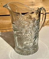 Full view of clear pressed glass pitcher showing pattern and handle