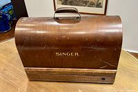 Front view of closed Singer wooden case showing logo and handle