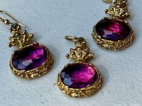 Front view of earrings and pendant showing purple stones and gold-tone settings