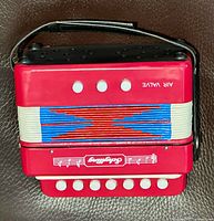 Front view showing Schylling logo, white buttons, air valve label, blue bellows