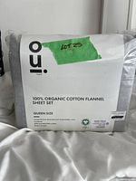 Front packaging view of OUI 100% Organic Cotton Flannel Sheet Set queen size in pale grey, showing brand and certification labels.