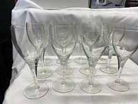 12 clear crystal wine glasses displayed on a white cloth background, showing the tall and short glasses together.