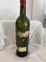 Full view of the 1937 Château Cheval Blanc empty wine bottle showing aged condition, label wear, and red foil capsule on top.