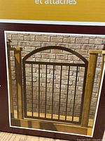 Photo of the arched metal deck gate outside of its box attached to a wooden frame, showing the gate design and black vertical bars with an arched top.