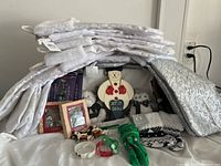 Overview of all items including stacked white and silver stockings with tags, plush snowman figure, decorative gloves, small framed pictures, and boxed ornaments.
