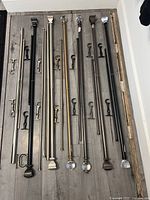 Full set of eight curtain rods with finials and mounting brackets laid out on wooden floor.