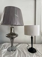 Front view of both lamps on white fabric against neutral wall showing size and design comparison