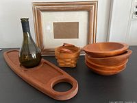 Photo showing the Longaberger basket, hand carved wine and cheese tray with bottle holder, four Marino wooden bowls stacked, and wooden picture frame with mat.