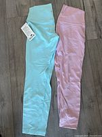Two pairs of pastel colored leggings laid flat on floor, blue and pink, showing length and fit
