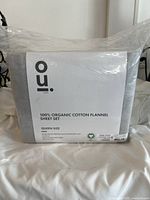 Photo showing packaging of OUI 100% Organic Cotton Flannel Sheet Set in queen size. The packaging clearly states the product details and brand.