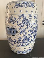 Side view of ceramic garden stool showing blue floral pattern and circular cut-out holes on the side.