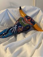 Side angle view of Talavera bull head showing colorful, detailed floral and abstract patterns with yellow horns and black tips.